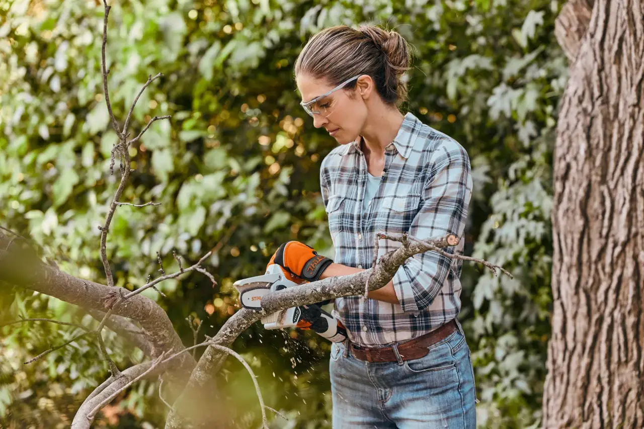 Gardener wearing safety glasses cutting through a branch with a STIHL GTA 26 battery garden pruner